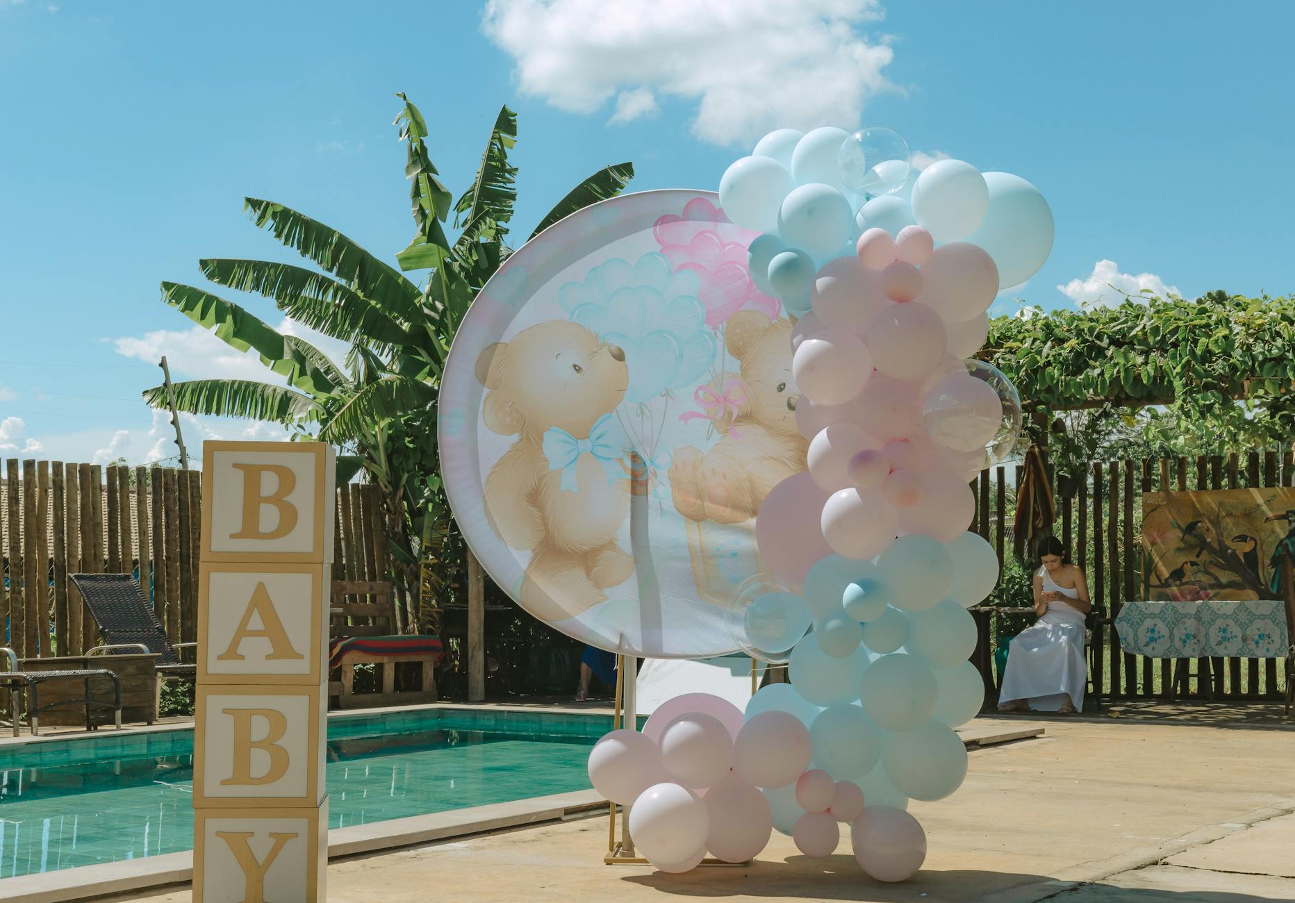 Charming outdoor baby shower setting with pastel balloons and a poolside backdrop in São Paulo.
