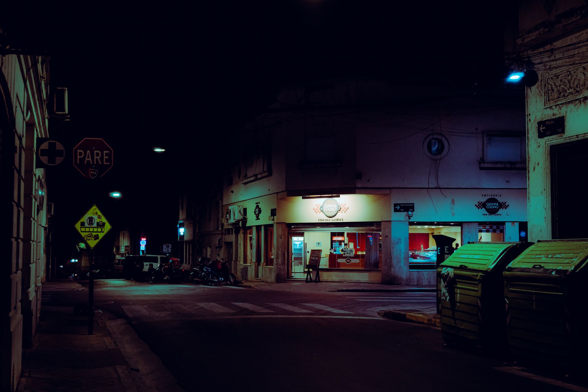 Moody night scene of a street in Rosario, Argentina with neon lights.