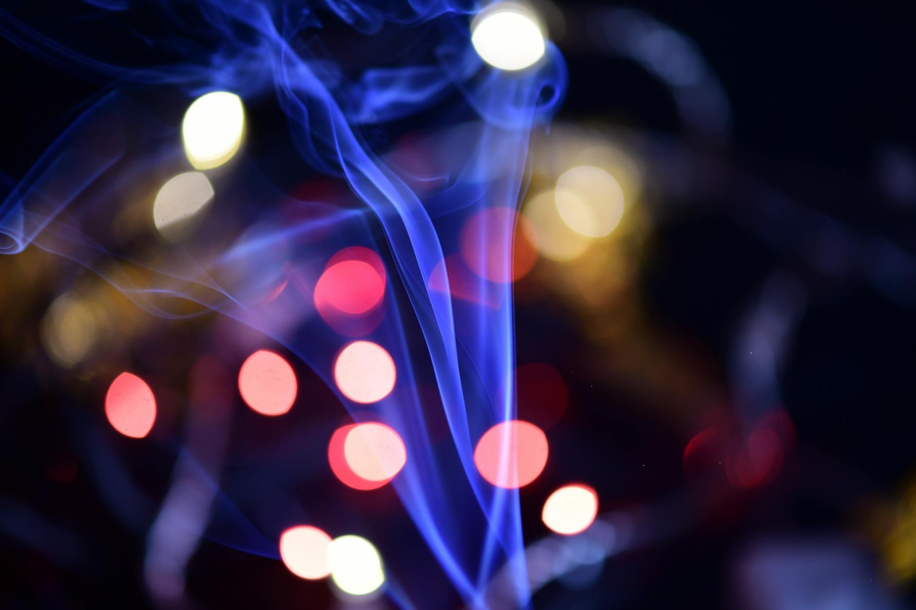 Vibrant abstract image featuring colorful bokeh lights and drifting blue smoke patterns.