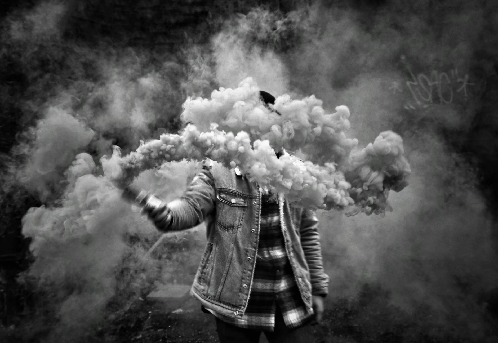 Black and white photo of a person holding smoke in İstanbul, creating a mysterious atmosphere.