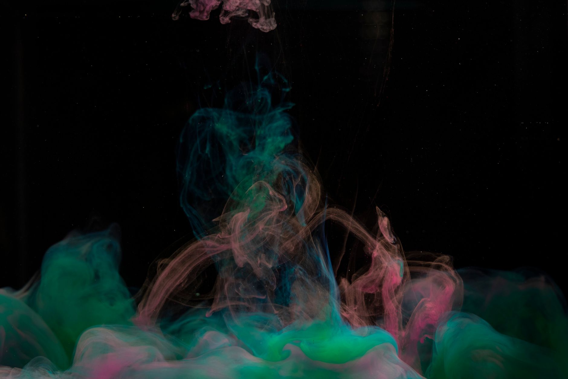 Vibrant colored smoke patterns swirl against a dark backdrop, creating a mesmerizing abstract art piece.