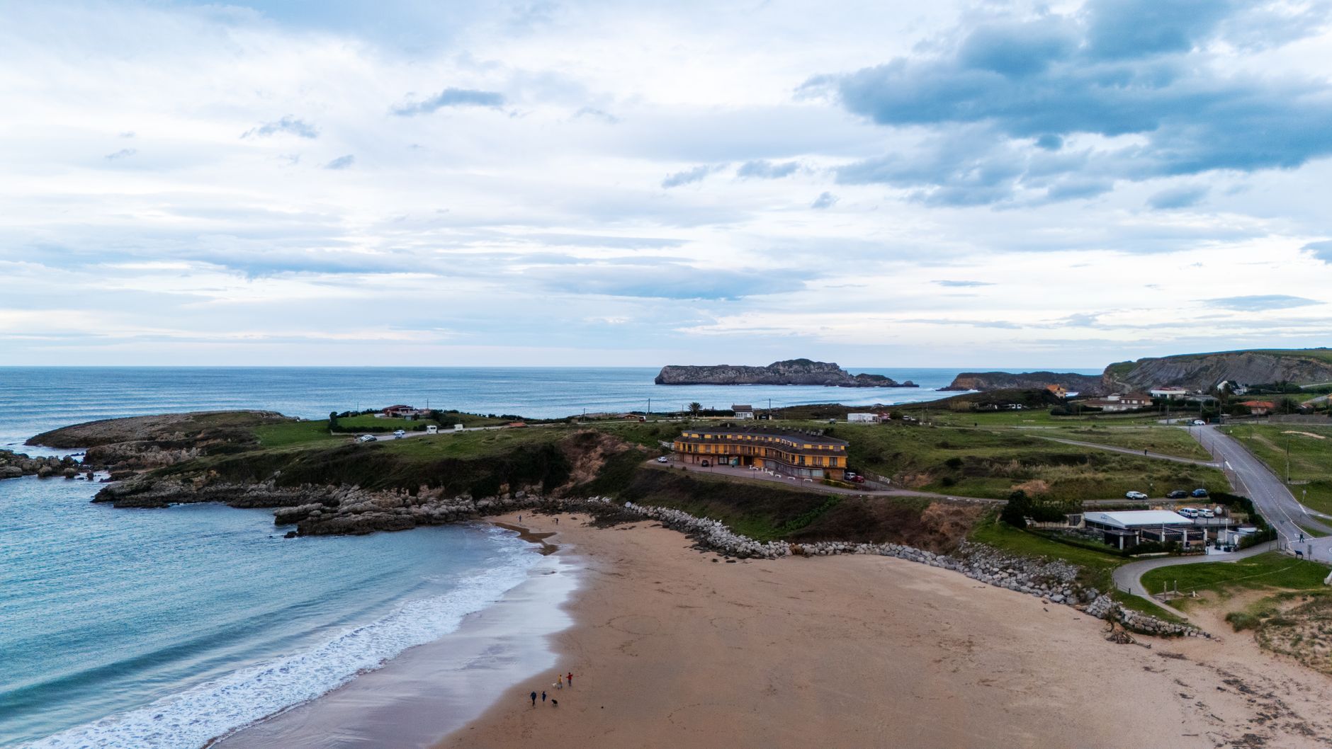 Aerial photo of Playa de Oyambre's coastline showcasing the sandy beach, lush greenery, and the ocean.