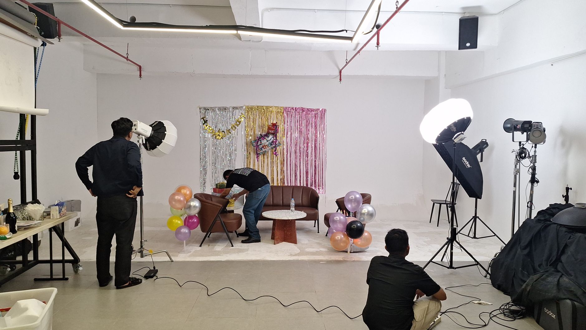 Photography studio setup with lighting equipment and colorful party decorations.