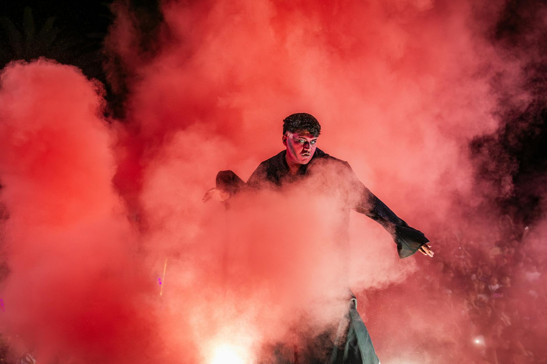 Performer in vibrant red smoke creates a dramatic scene at Arica carnival.