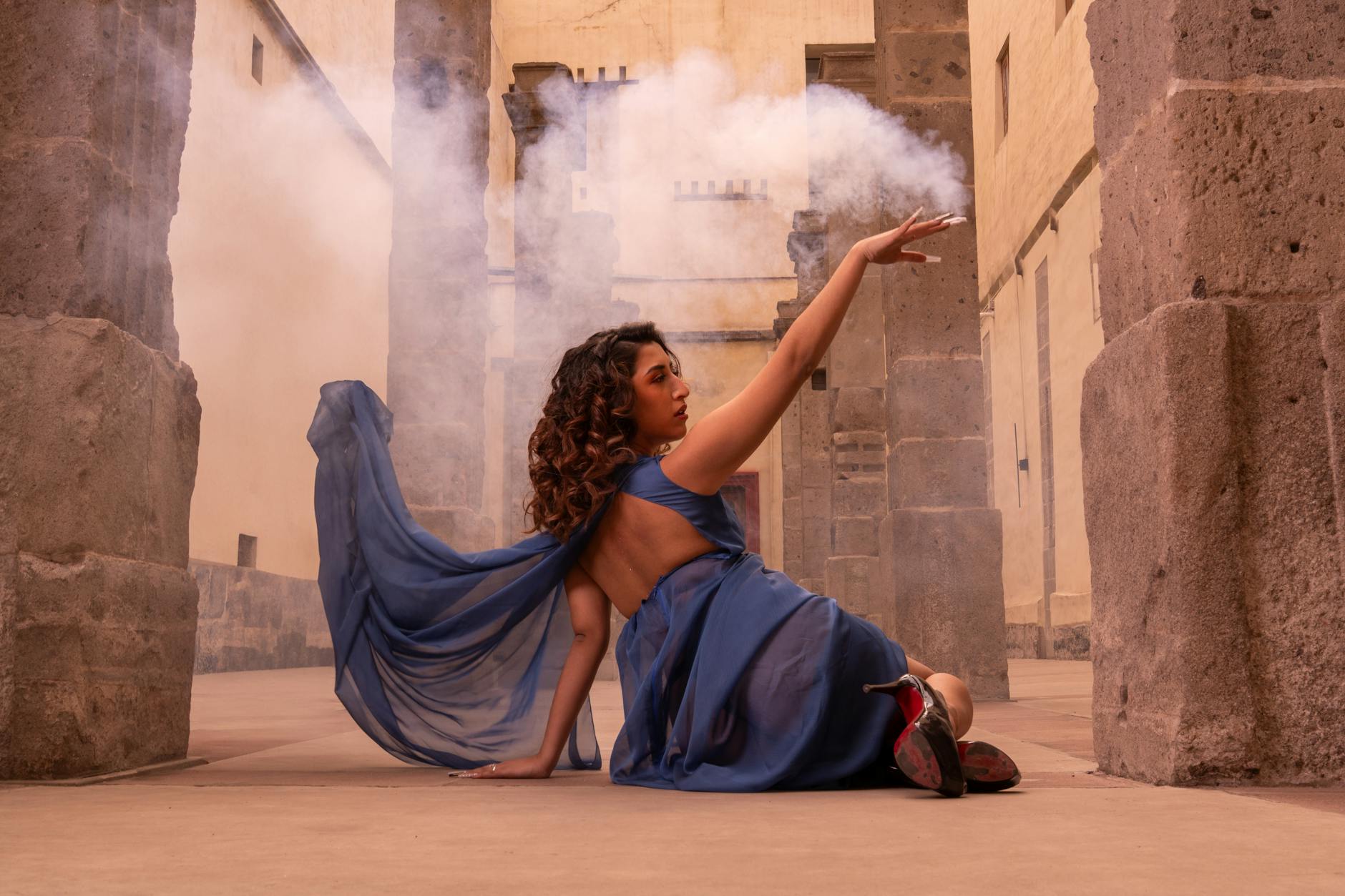 A woman in a flowing blue dress poses artistically in a historic courtyard in Ciudad de México.