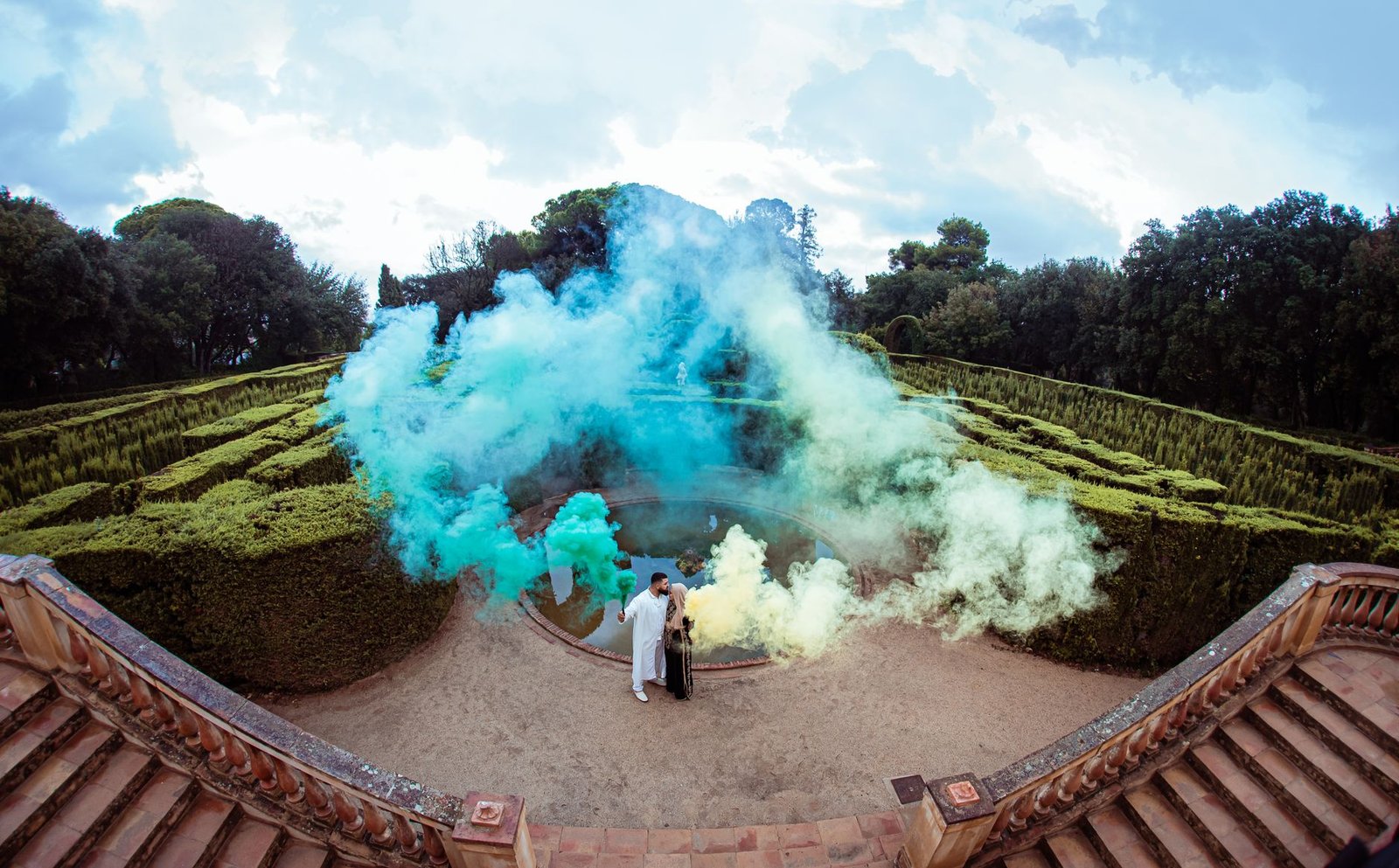 A couple enjoys vibrant smoke effects in Barcelona's historic Labyrinth Park.