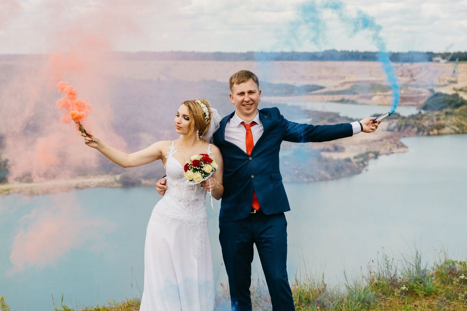 Bride and groom celebrating with colorful smoke on a scenic outdoor wedding day.