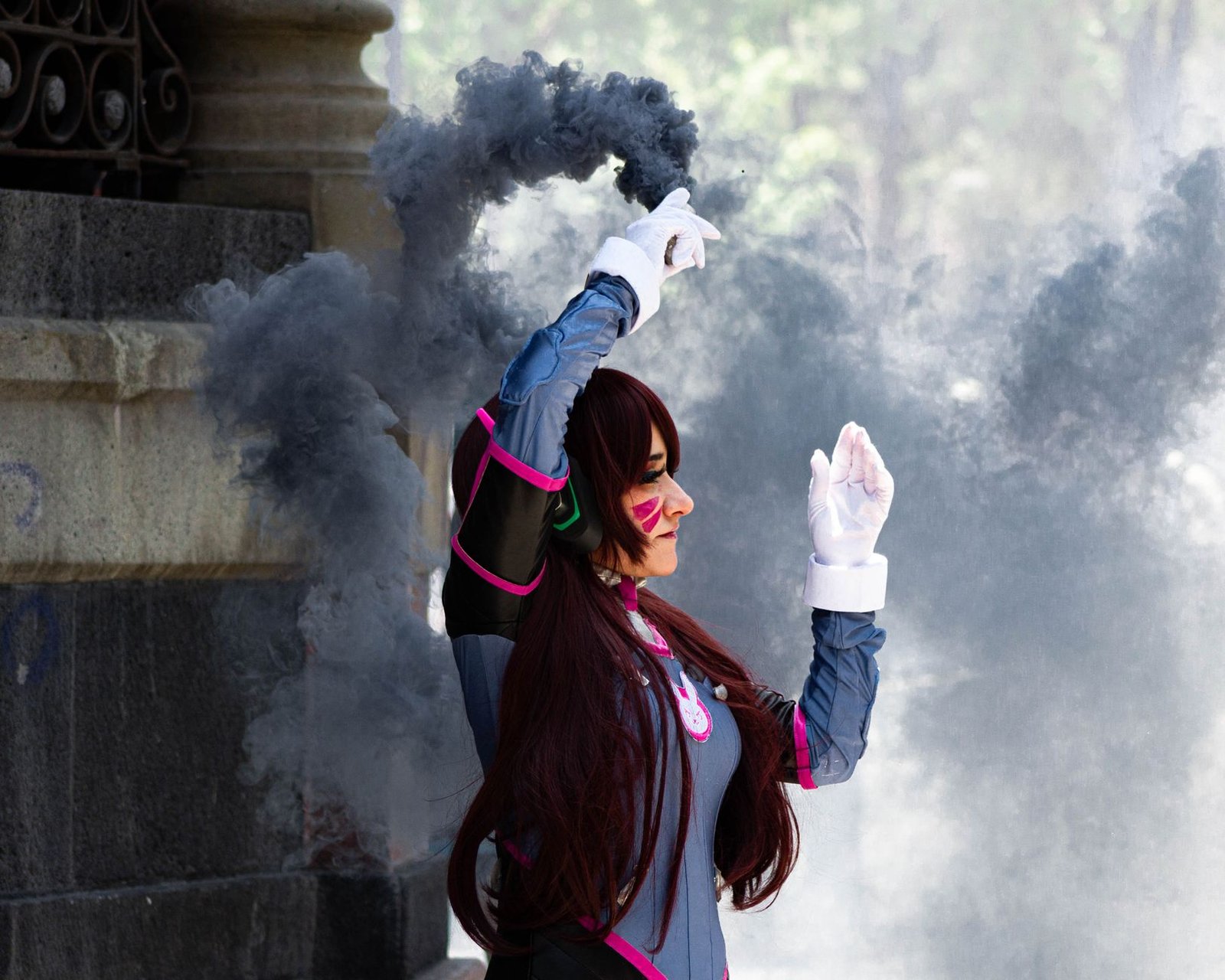 A cosplayer dressed in detailed costume poses with smoke in an outdoor setting. Stylish and dynamic scene.