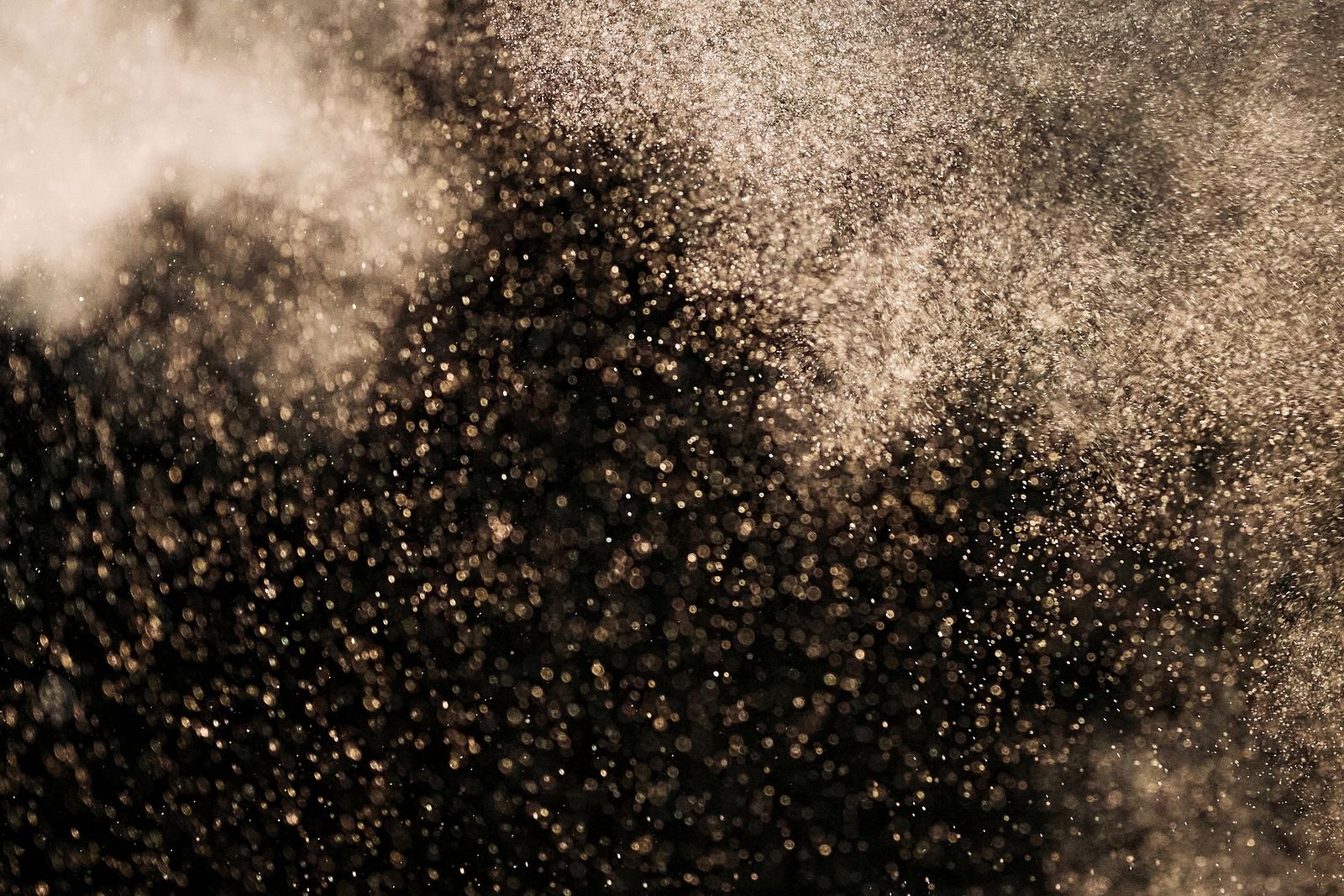 Stunning abstract image featuring gold particles floating against a dark background, creating a magical atmosphere.