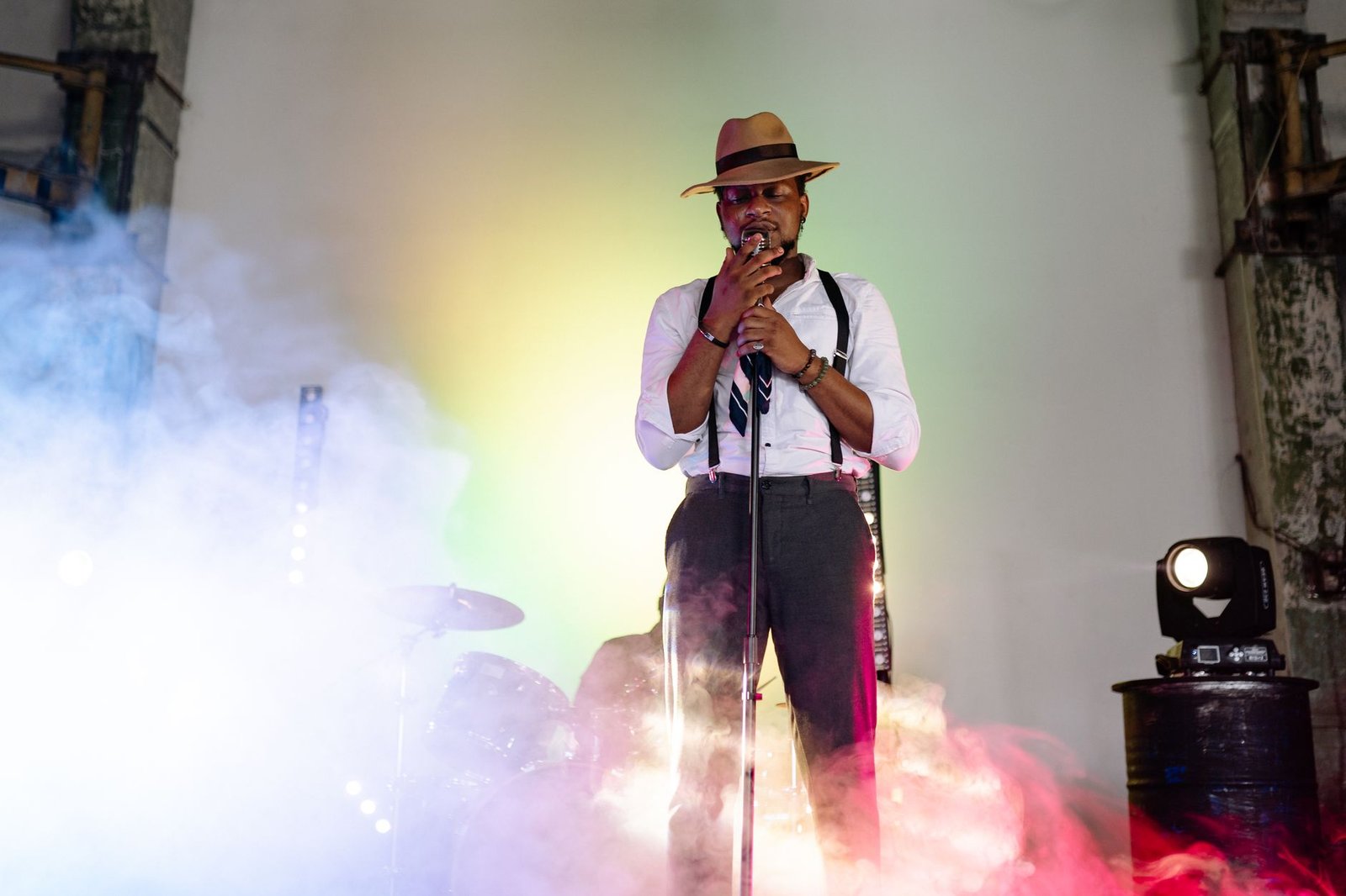 A charismatic singer performs on stage with vibrant lighting and smoke effects, adding intensity to the ambiance.