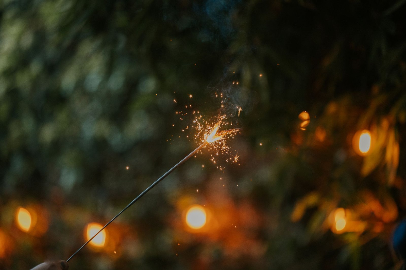 Close-up of a sparkler in hand against a blurred bokeh background, perfect for festive occasions.