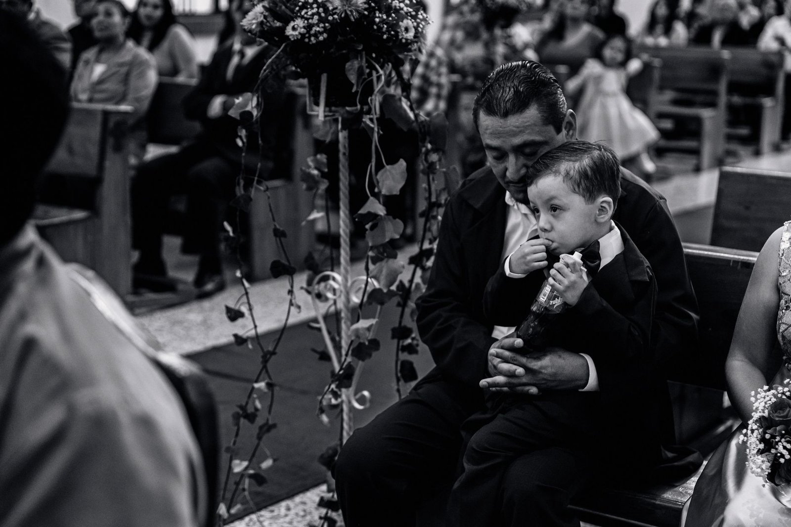 Intimate black and white photo of a father and son during a church ceremony.